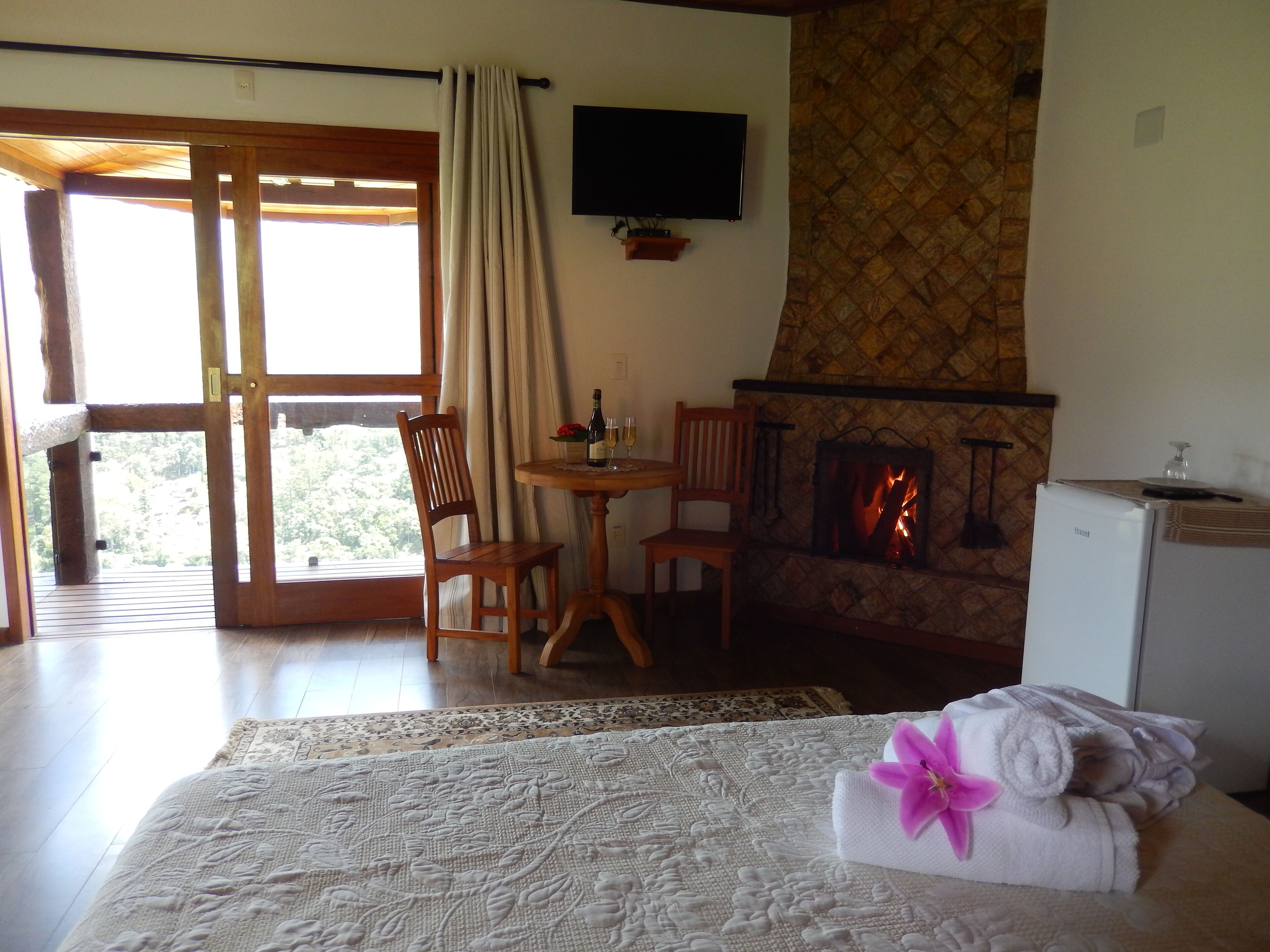 A cozy room with a bed, a fireplace, a television, and a dining area with chairs and a table.