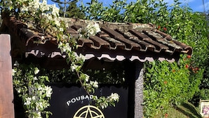Un letrero con el texto "POUSADA SONHO" y un símbolo de pentagrama.