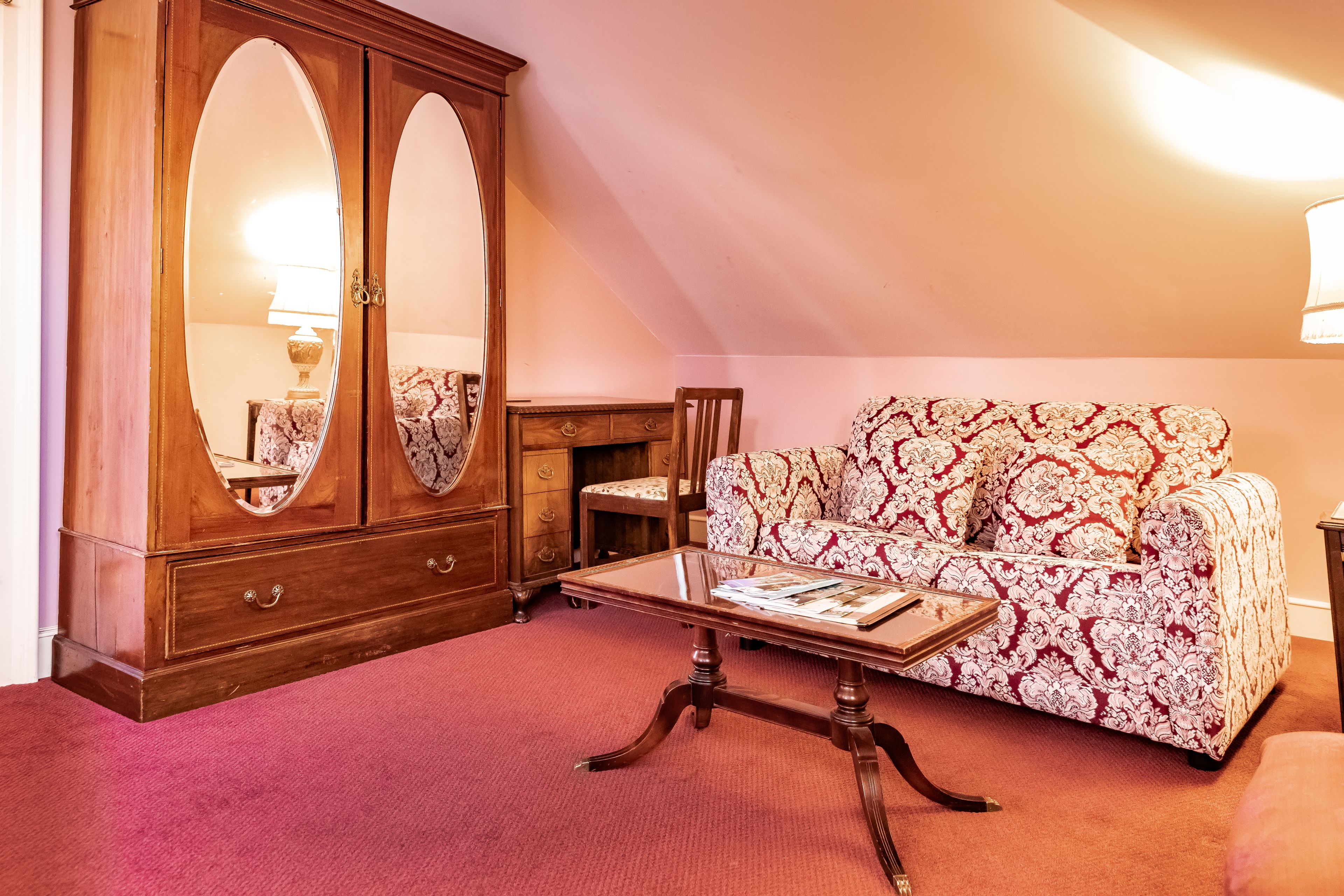 Una habitación con un armario de madera, un sofá estampado y una mesa de centro.