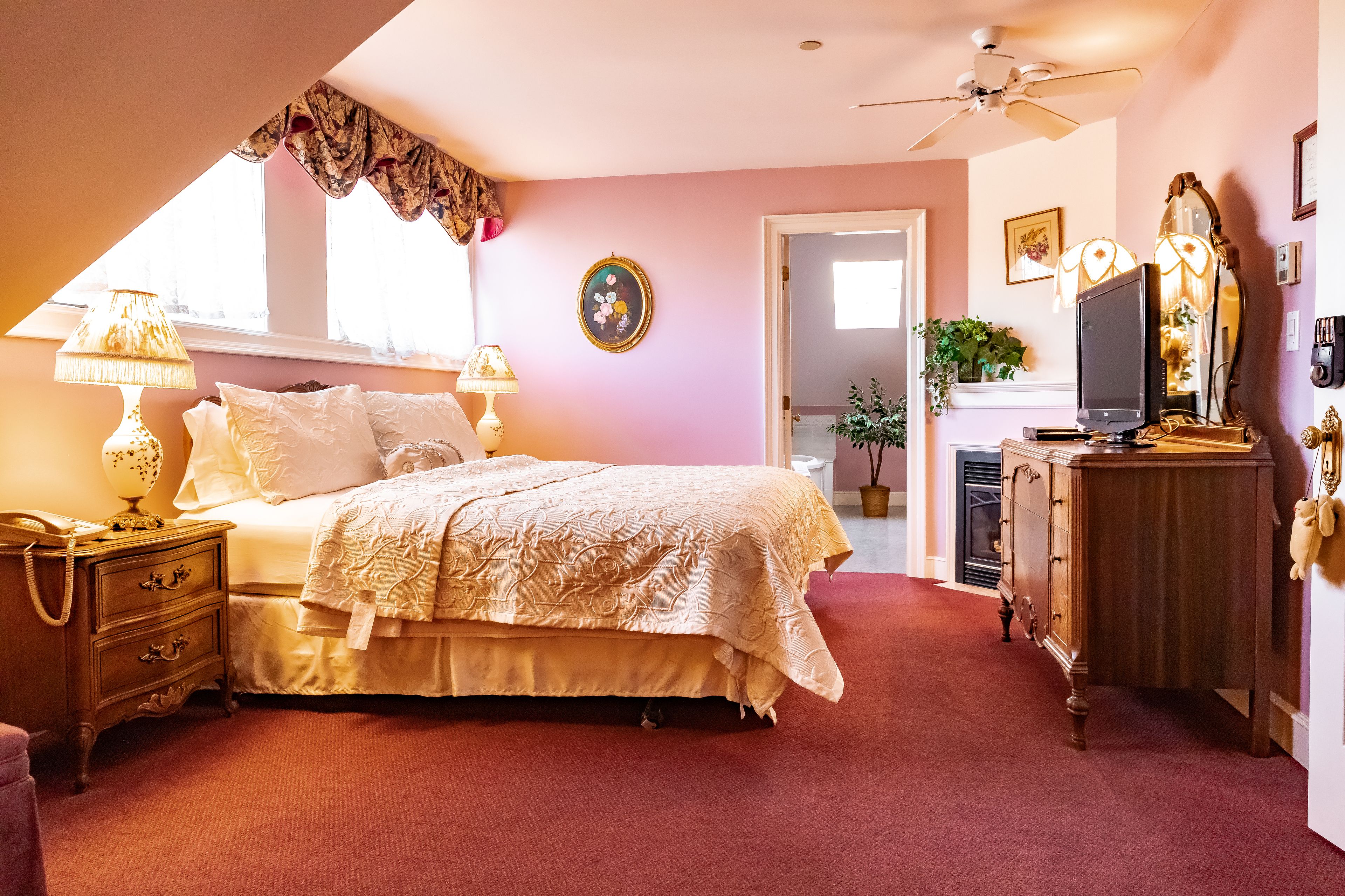 A bedroom with a bed, dresser, lamp, and a television.
