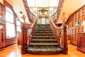 A grand staircase with ornate railings and a floral carpet, leading to a landing with a potted plant. - Amethyst Inn at Regents Park (Victoria)