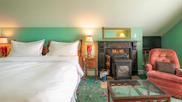A bedroom with a bed, a fireplace, a chair, and a small table.