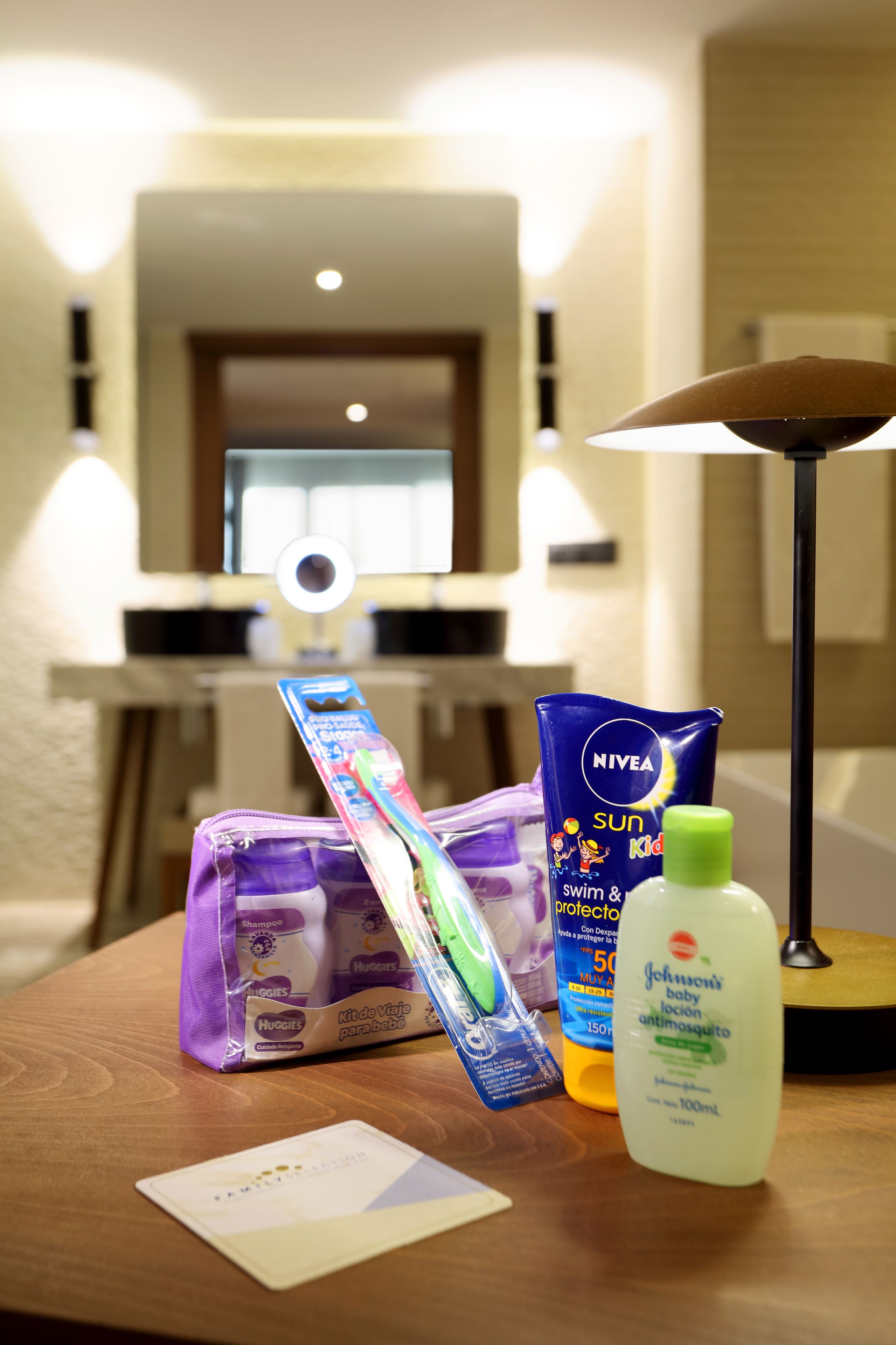 A table with toiletries including a shampoo bottle, a baby lotion, and a tube of sunscreen.