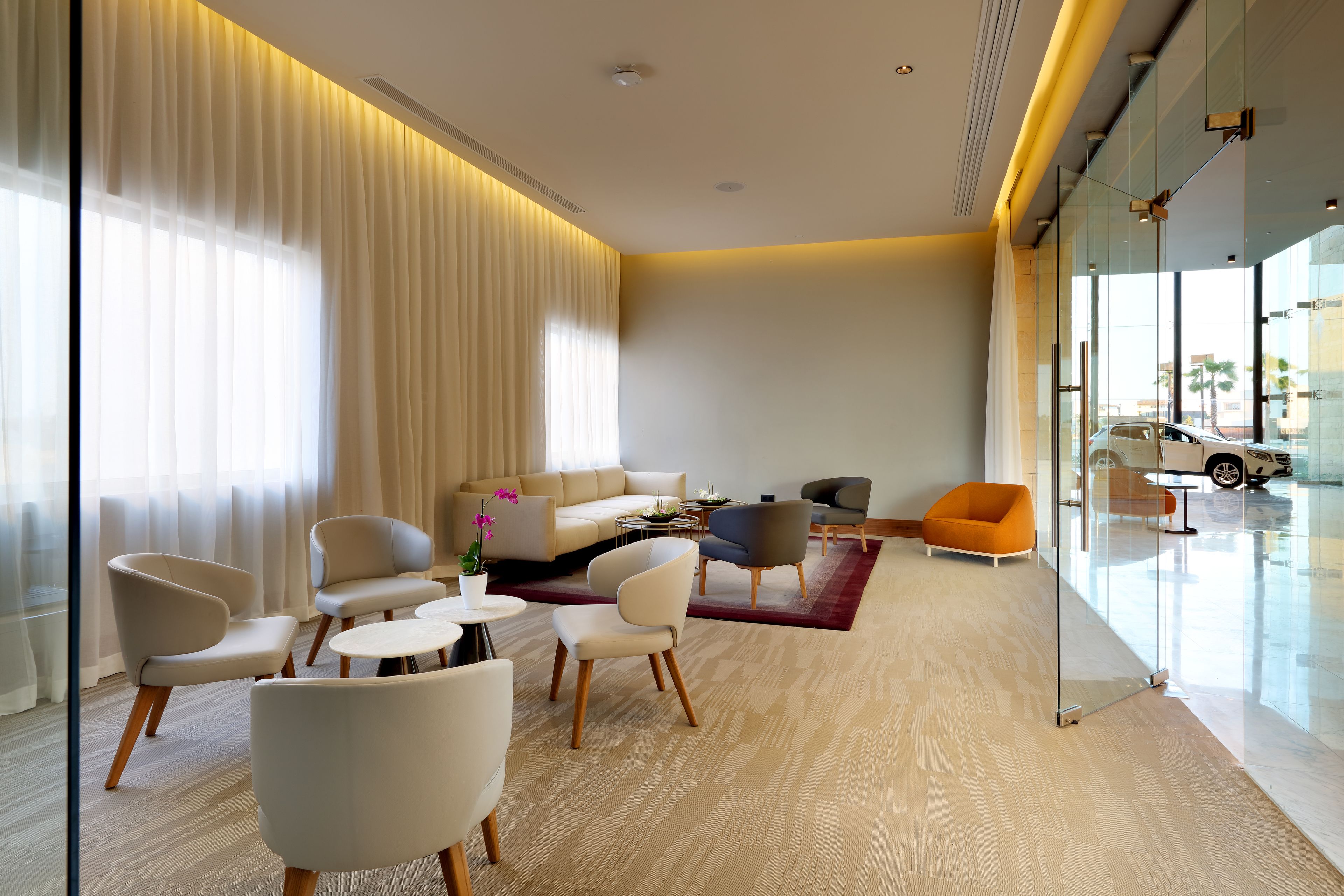 A modern living room with a sofa, armchairs, a coffee table, and a glass partition.