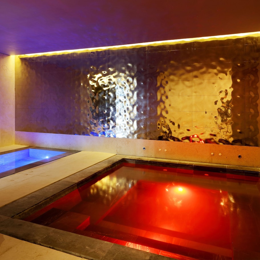 A spa area with two separate pools, one with blue lighting and the other with red lighting.