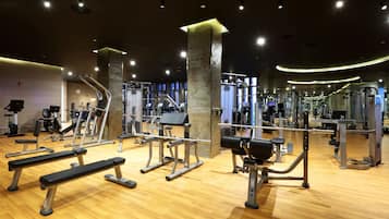 A gym with various exercise equipment, wooden flooring, and a modern design.