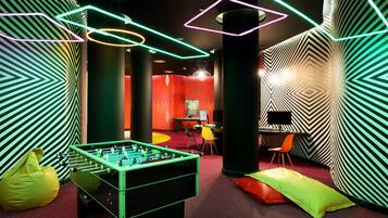 A room with a foosball table, bean bag chairs, and a desk with a computer.