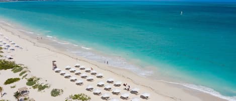 On the beach, white sand, sun loungers, beach umbrellas