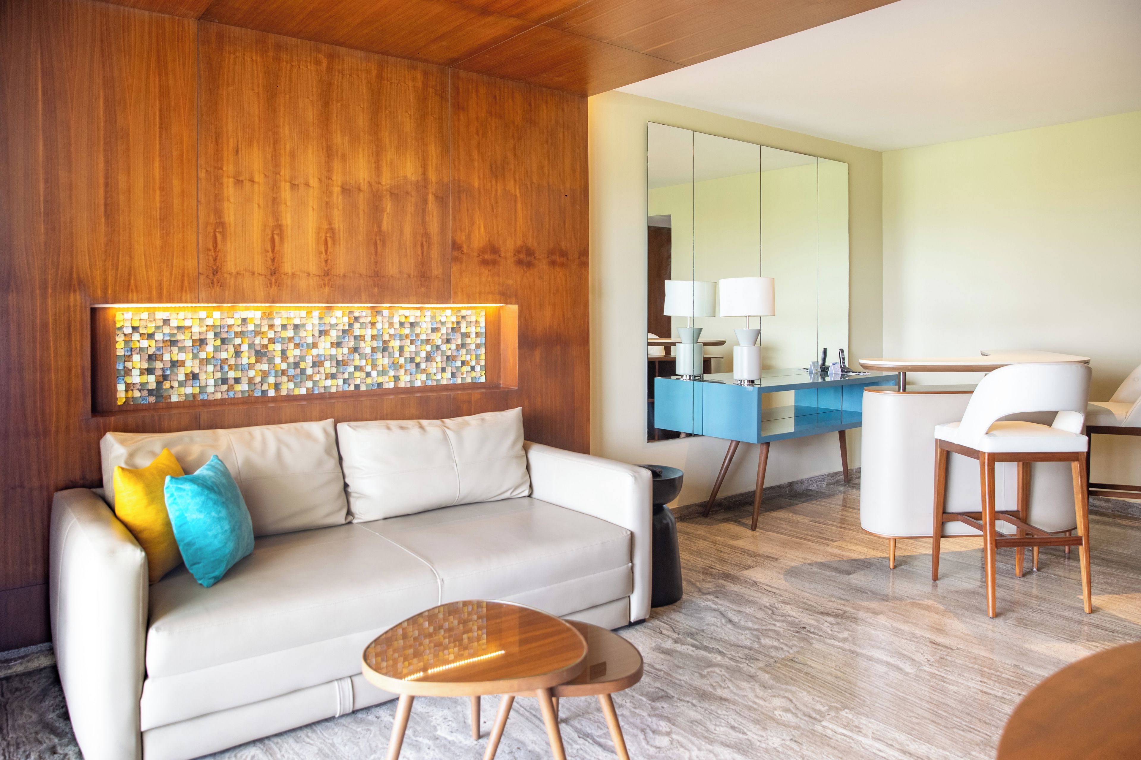 Een moderne woonkamer met een bank, een salontafel, en een eethoek met een blauwe kast en stoelen.