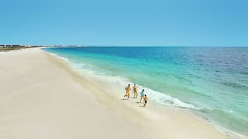 På stranden, vit sandstrand, solstolar och parasoller