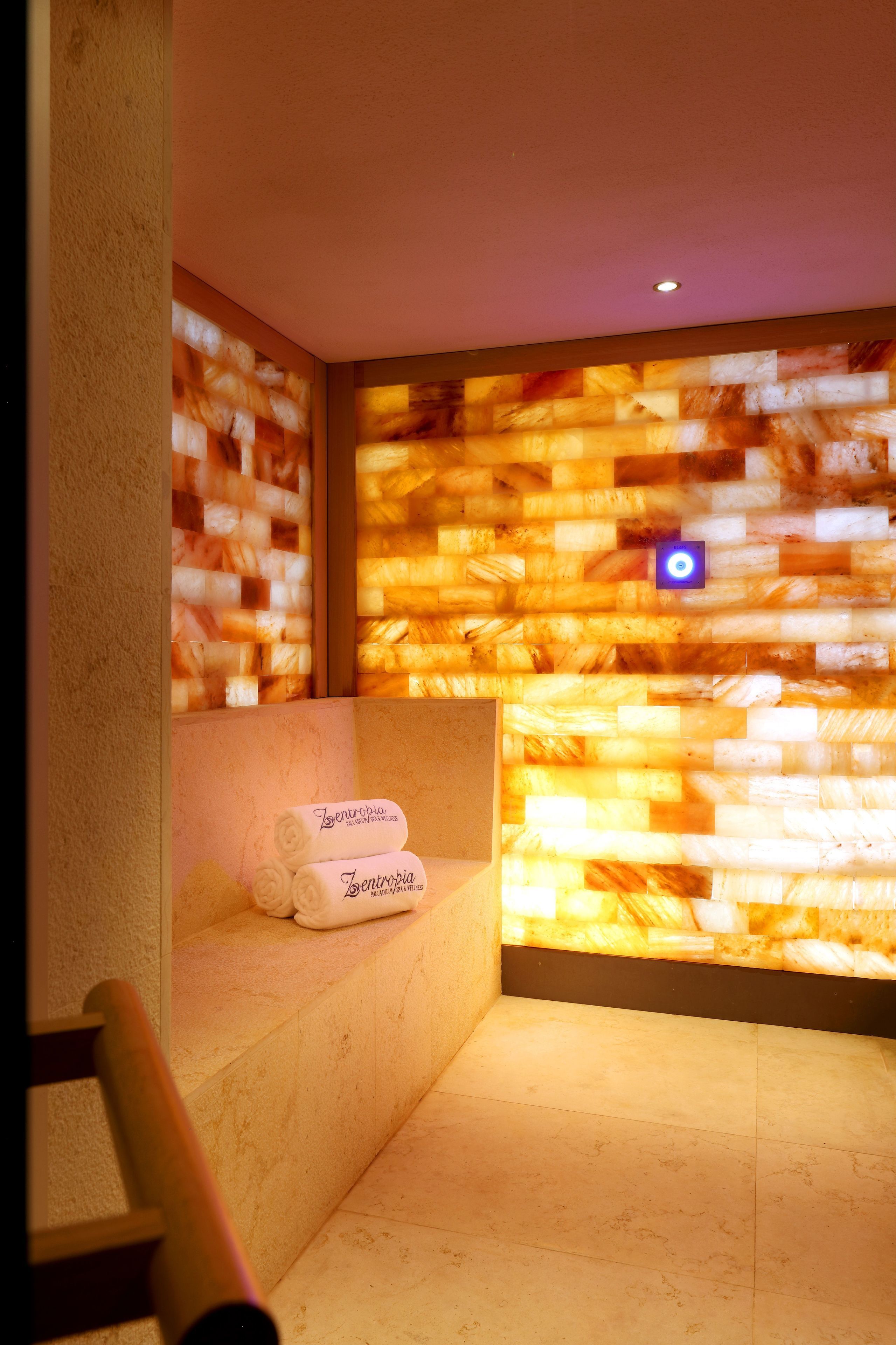 A spa room with a massage table, a wall with a textured pattern, and a towel on the table.