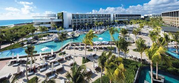 Un resort con varias piscinas, palmeras y edificios modernos.