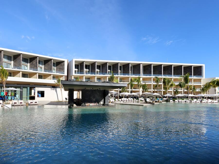 Un hotel moderno con zona de piscina, varios balcones y mobiliario exterior.