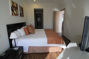 Una habitación de hotel con cama, mesita de noche, lámpara y televisor.
