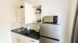 Una cocina compacta con microondas integrado, refrigerador de acero inoxidable y pileta.