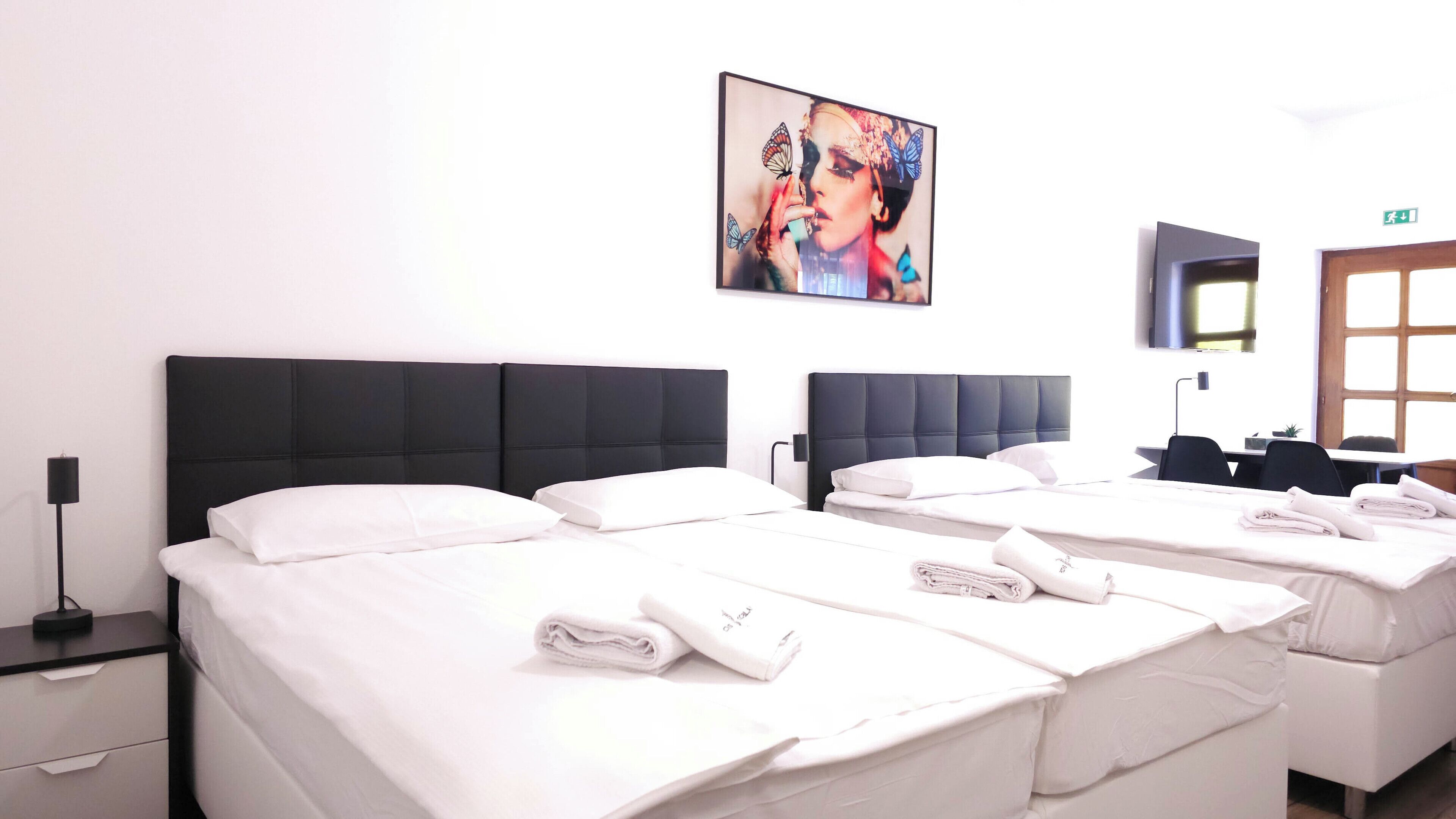 A hotel room with two beds, white linens, and a painting on the wall.