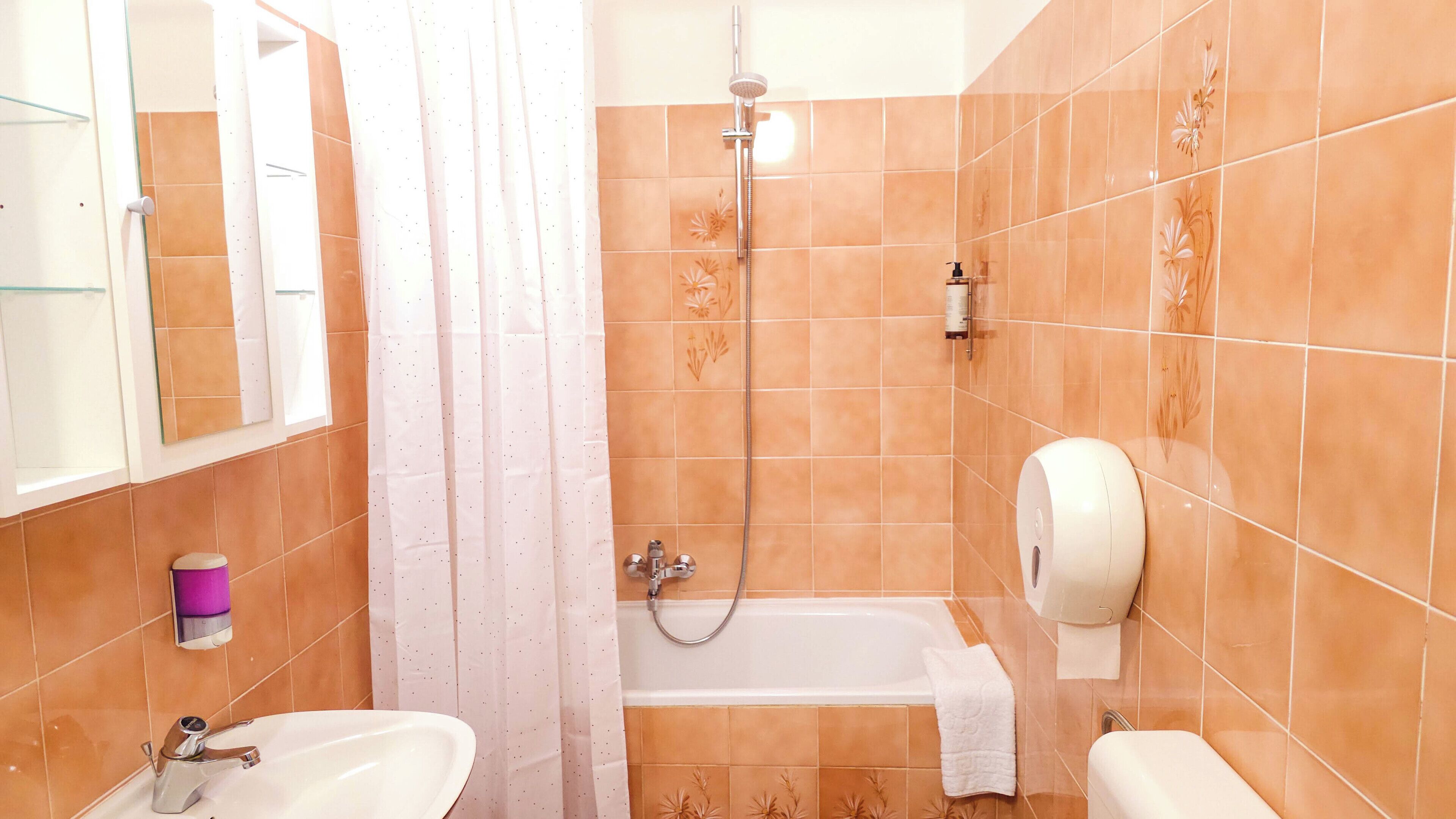 A bathroom with a shower, two sinks, a toilet, and a towel rack.