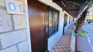 A hotel entrance with a numbered door, a covered walkway, and a parking lot in the background. - Rooms Koblar (Piran)