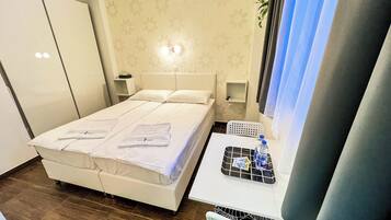 A hotel room with a bed, bedside tables, a small table with a tray of toiletries, and a wardrobe.