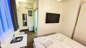 A hotel room with a bed, a TV, a small table with a water bottle, and a mirror. - Rooms Koblar (Piran)