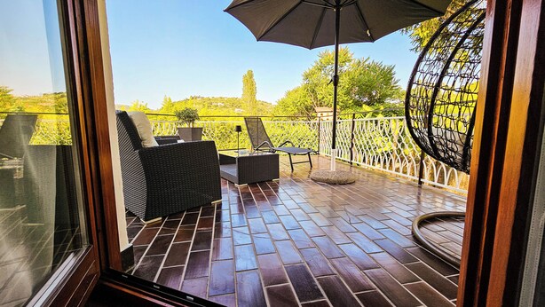 A balcony with wicker furniture, a table, and an umbrella. - Rooms Koblar (Piran)