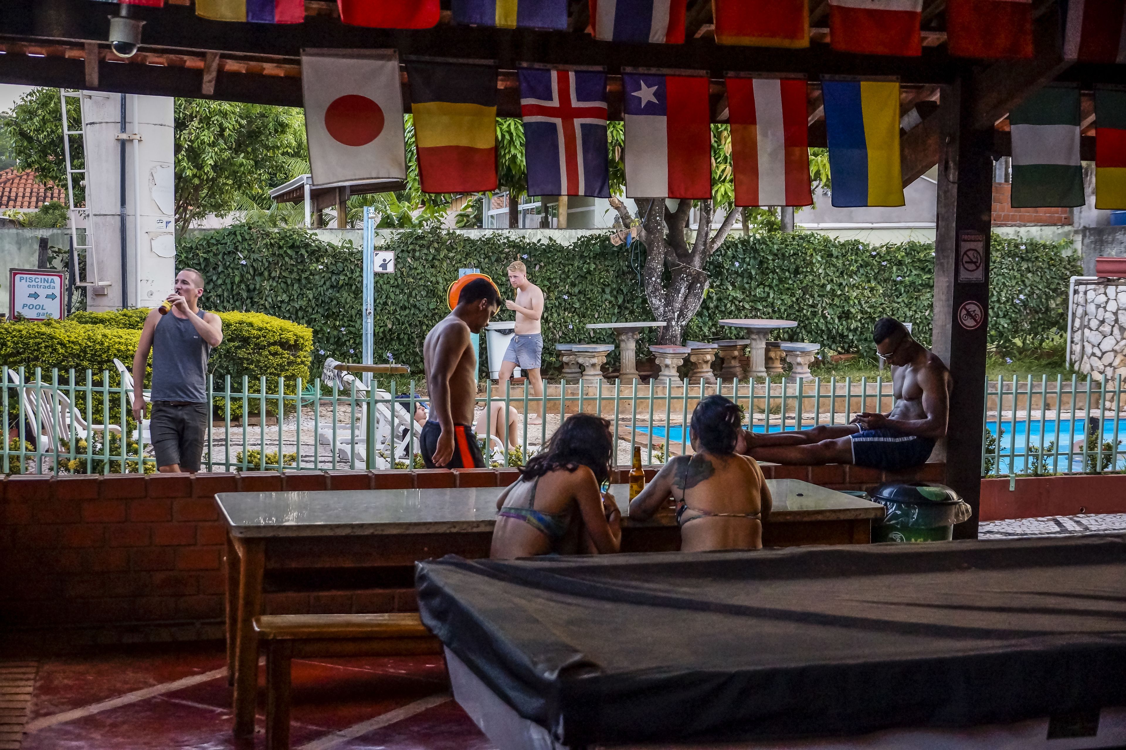 A covered outdoor area with a pool, benches, and flags.