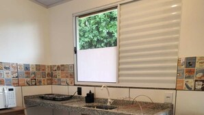 A compact kitchen with a window, a microwave, a sink, and a vintage refrigerator. - Bonito Hi Hostel e Pousada (Bonito)