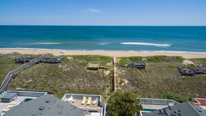 Une vue sur la plage, avec une promenade en bois menant au rivage, une plage de sable et un ciel bleu dégagé.