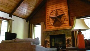 A cozy living room with a fireplace, a ceiling fan, and a television. - The Preserve, Craftsman Special Vacation Home (Fall Creek Falls)
