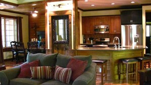 A cozy living room with a sofa and a dining area, a kitchen with modern appliances, and a large wooden ceiling. - The Preserve, Craftsman Special Vacation Home (Fall Creek Falls)