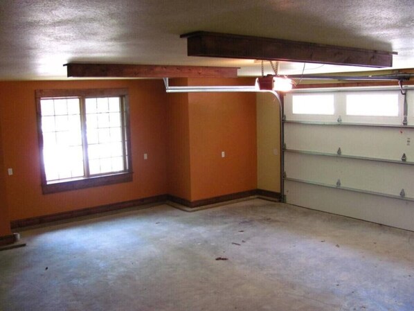 A room with a large window, a garage door, and a wooden beam ceiling.