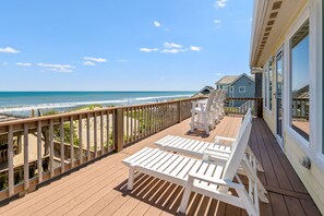 A wooden deck with white lounge chairs overlooking a beach. - Leg-a-Sea: Oceanfront, Pool Access, Hot Tub (Nags Head)