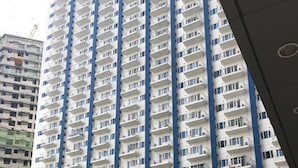 A high-rise residential building with multiple balconies and a swimming pool in the foreground. - Light Residences - One Bedroom Condo Unit (Mandaluyong)