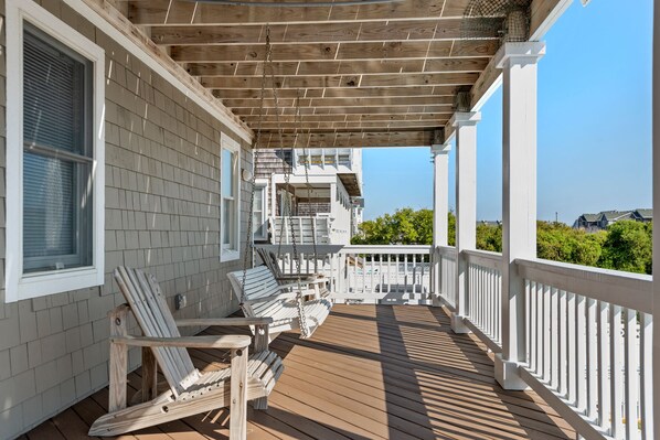 A wooden deck with white railings and a covered area.