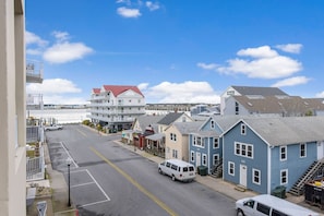 A street view with a white van parked on the side, a blue building with a red roof, and a white building with a red roof.