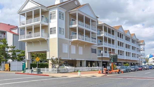 A multi-story hotel with balconies, a covered entrance, and a parking area. - Unique, festive 3-bedroom luxury condo with adorable coastal decor and free WiFi located downtown on the bayside and just two blocks to the beach and Boardwalk! (Ocean City)