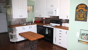 Una cocina con armarios blancos, encimera de madera, estufa y fregadero.