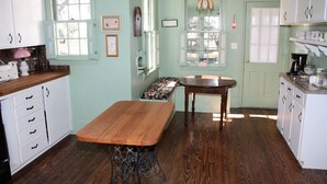 Una cocina con mesa de madera, armarios blancos y una banca junto a la ventana.