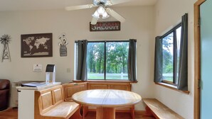A room with a round wooden table, benches, a ceiling fan, a world map, and a sign that reads 'SALOOY.' - Family Friendly Farm Stay Near Yosemite (Mariposa)