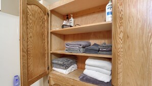 A wooden cabinet with shelves holding folded towels and toiletries. - Family Friendly Farm Stay Near Yosemite (Mariposa)