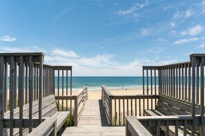 A wooden boardwalk leading to a beach with a clear sky.