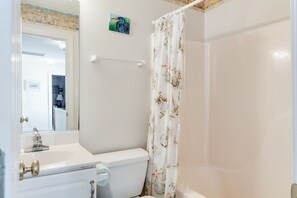 A bathroom with a white sink, toilet, and shower curtain with a floral pattern.