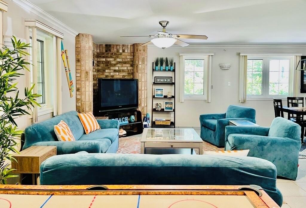 Una sala de estar con televisión, sofás azules, una mesa de centro y una chimenea.