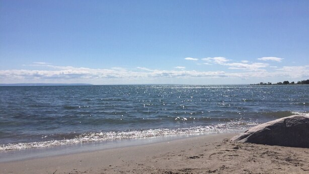 Een strand met heldere lucht en rustig water.
