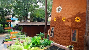 Een landelijk gebouw met een lemen gevel, een klein raam en een bord met de wegwijzer naar verschillende voorzieningen, zoals een galerie, Thaans massage en een kleihuis.
