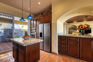 A kitchen with a central island, stainless steel appliances, and a decorative vase with flowers.