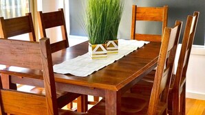 Una mesa de comedor de madera con cuatro sillas, un camino de mesa blanco y dos jarrones decorativos con diseño geométrico.