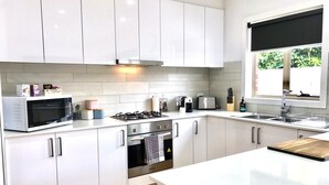 Una cocina moderna con armarios blancos, estufa de acero inoxidable y un amplio ventanal.