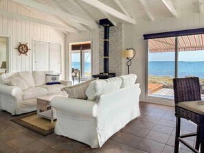 Un salón costero con un sofá blanco, un sillón de mimbre y vistas al mar.