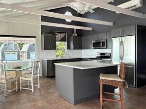 Una cocina moderna con una isla grande, muebles oscuros y electrodomésticos de acero inoxidable.